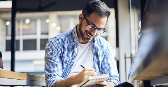 Smiling businessman working with pen and paper.