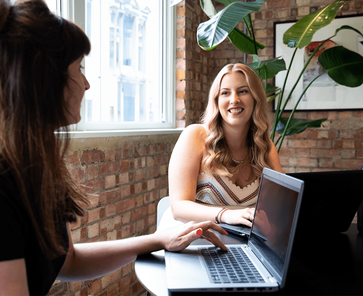 Two smiling females at work, laughing.