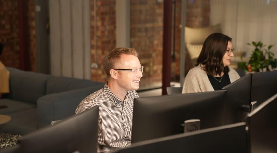 Male and female working on their computers smiling.