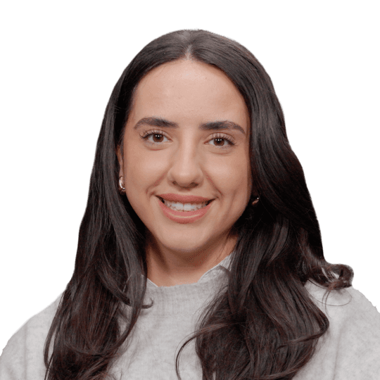 Smiling female receptionist with long brown hair wearing a grey jumper.