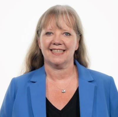 Portrait of a smiling blonde female wearing a blue blazer.