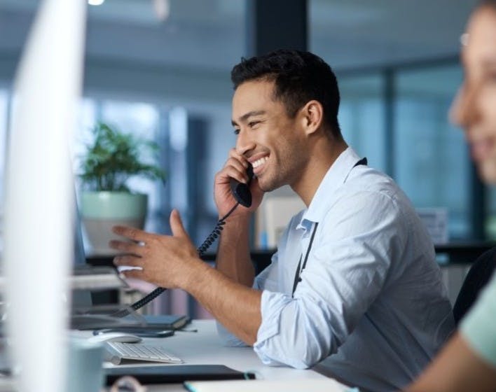 Smiling male receptionist on the phone whilst working in a call centre.