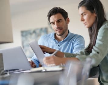 A male and a female lawyer working in a modern office with laptops.