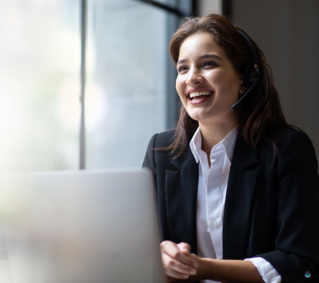 Virtual PA wearing a dark jacket with white shirt, working in an office using a VOIP helpdesk headset.