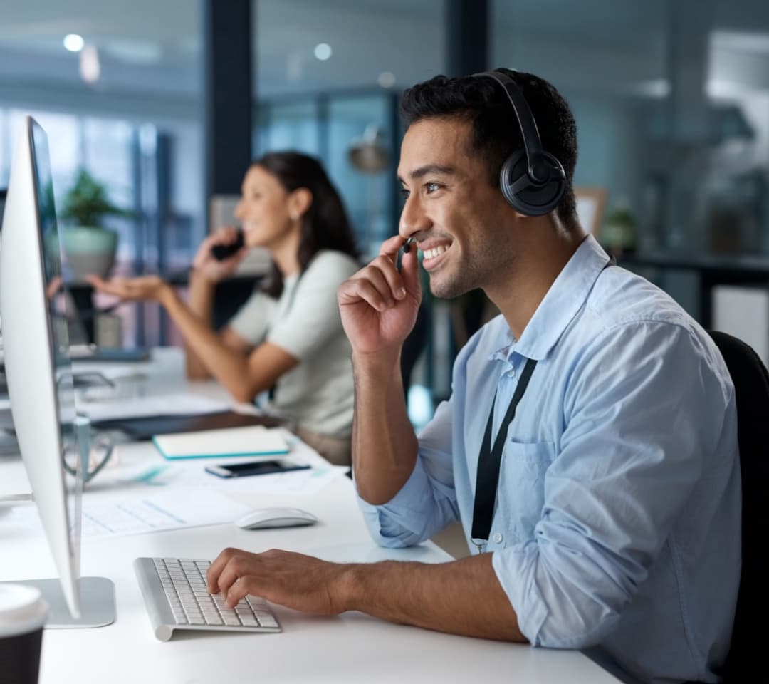 Customer service agent with headset sat at an office desk, demonstrating how to improve customer communication.