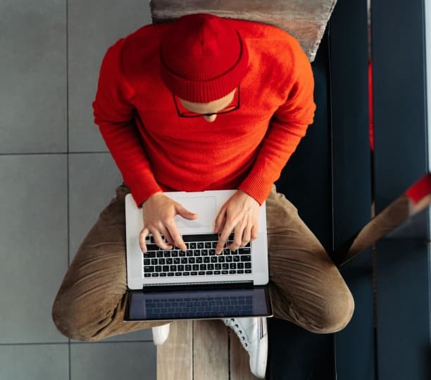 An overhead shot of a man sat down working on his laptop.