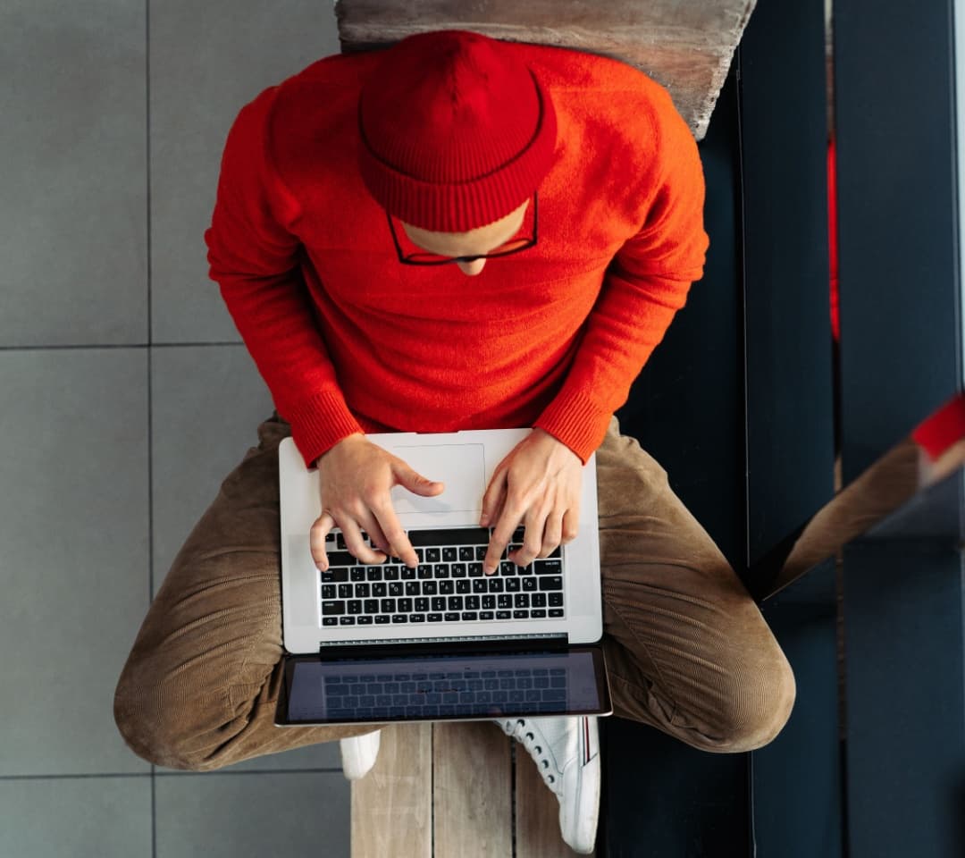 An overhead shot of a man sat down working on his laptop.