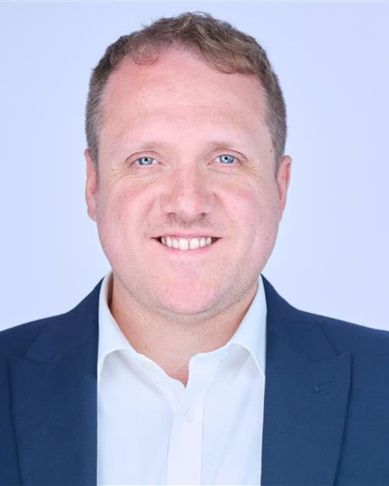 Portrait of caucasian male wearing a blue blazer and white shirt smiling at the camera