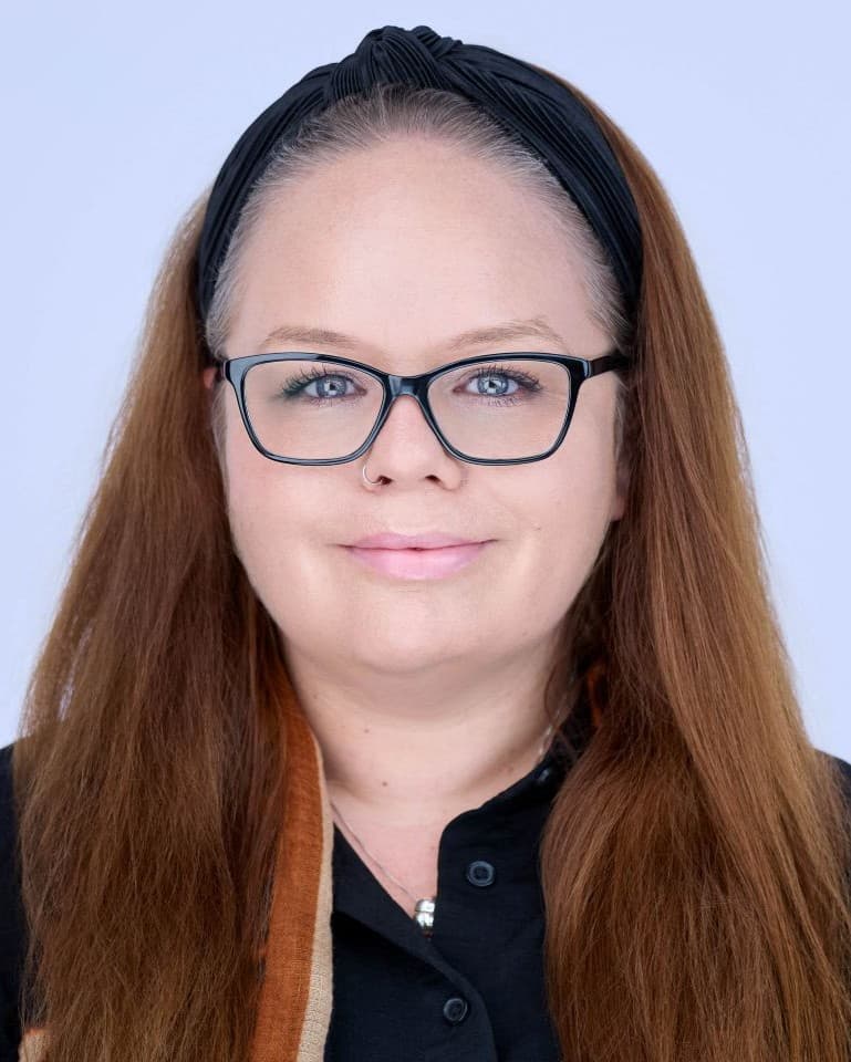 Portrait of smiling red haired, female training manager with glasses